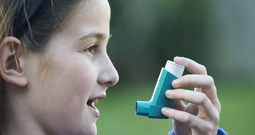 Girl Using Inhaler To Treat Asthma Attack